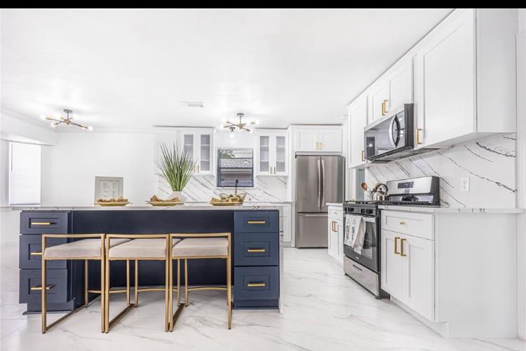 Our cabinet work: white kitchen cabinets with a navy blue island and gold hardware