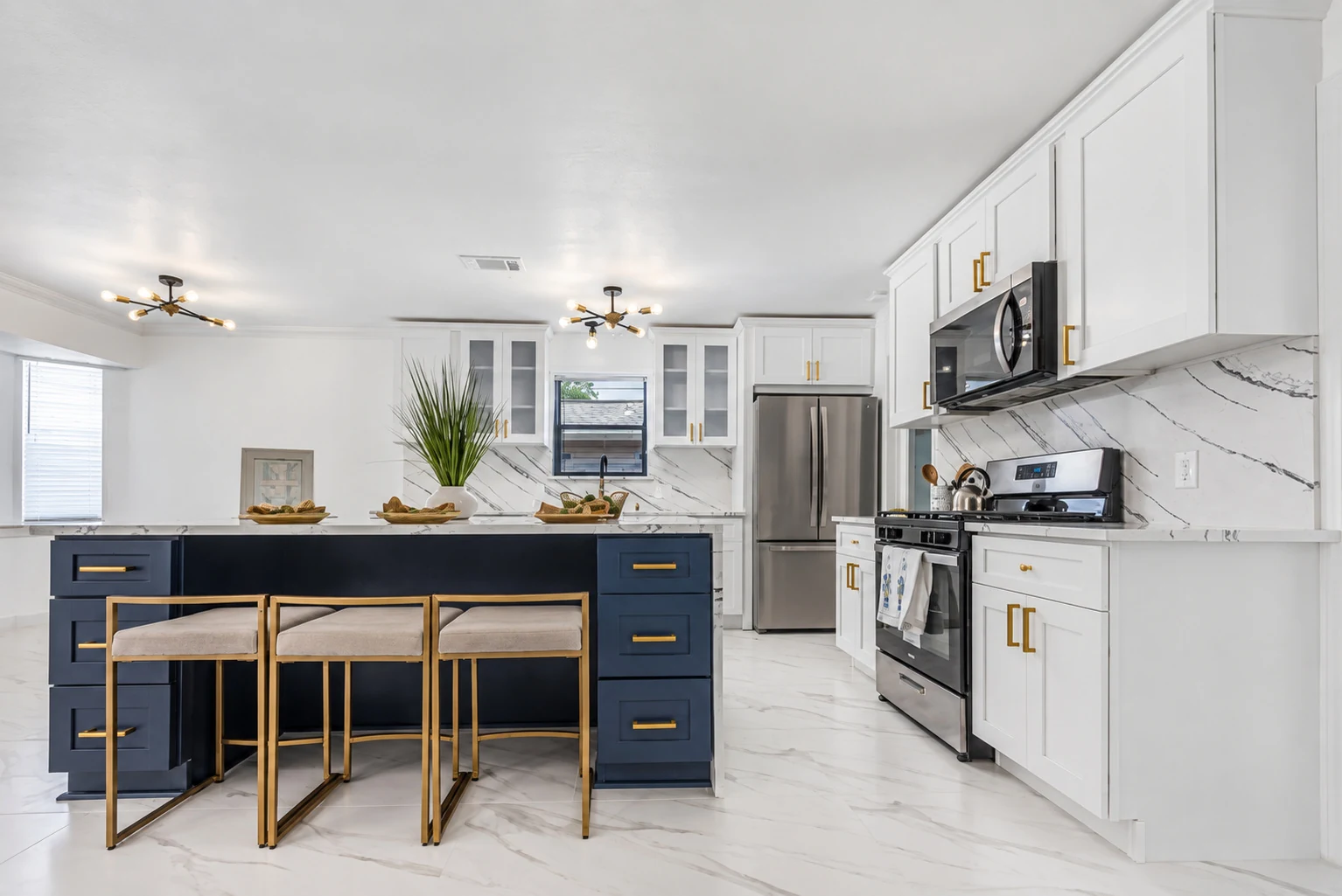 White shaker cabinets with gold hardware and a contrasting navy island
