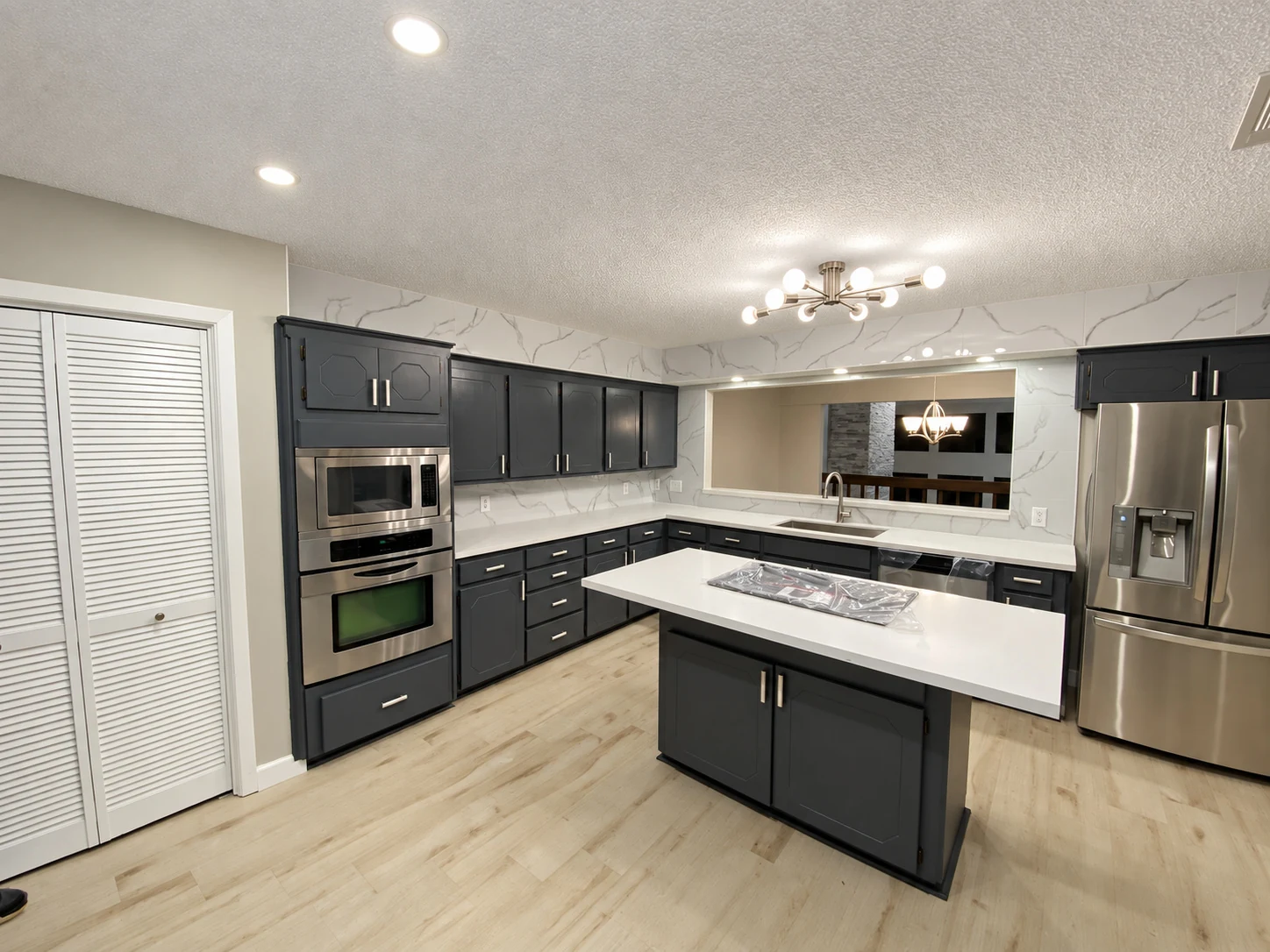 Dark cabinets around a central island, with light countertops and silver pulls