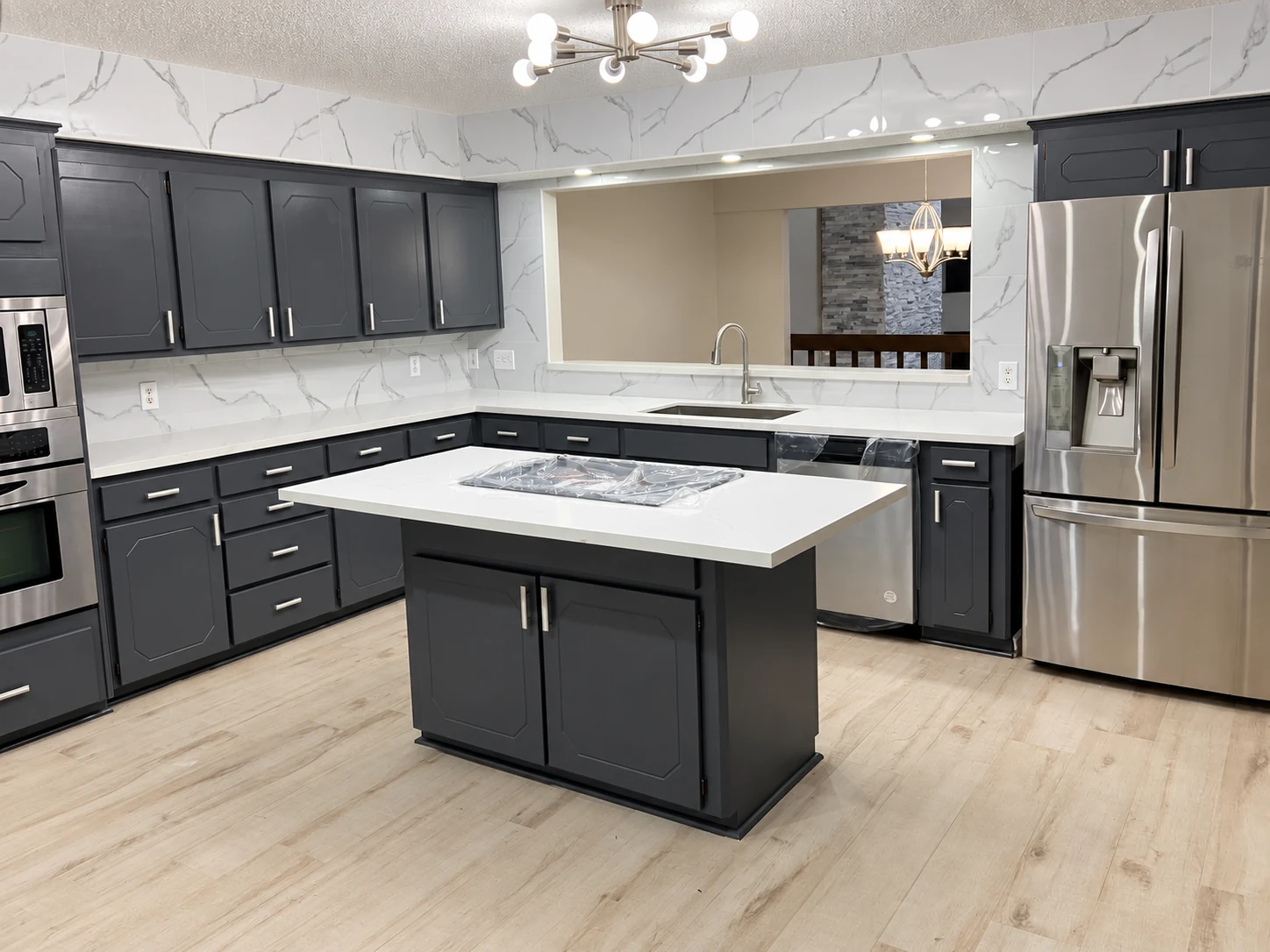 Dark cabinets around a central island, with light countertops and silver pulls — another view