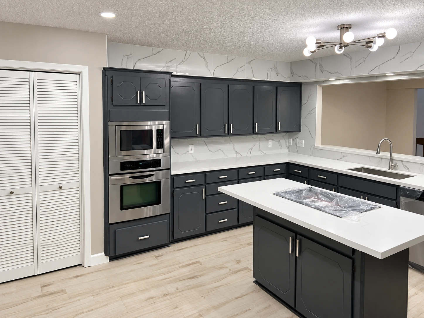 Dark cabinets around a central island, with light countertops and silver pulls — another view