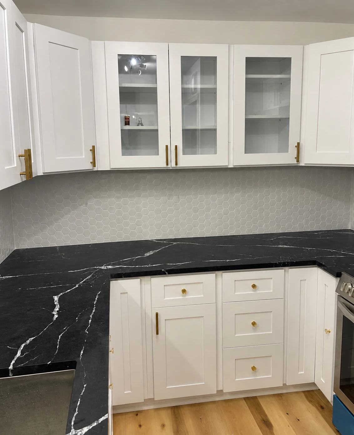 White cabinets and glass-front uppers alongside dark, veined countertops — another view