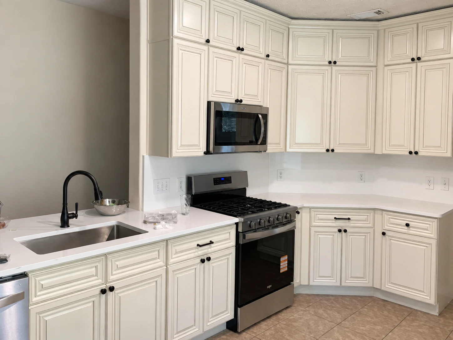 White raised-panel cabinet doors with dark knobs and a black faucet — another view